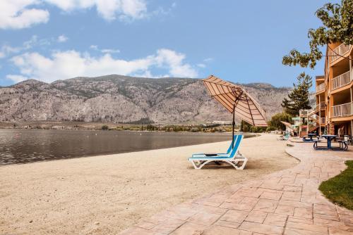 a beach with a chair and an umbrella at Coast Osoyoos Beach Hotel in Osoyoos