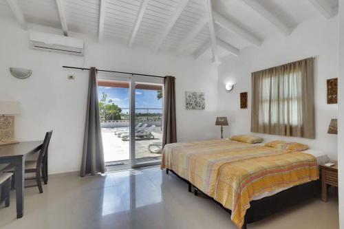 a bedroom with a bed and a desk and a window at Villa Salinja Breeze in Kralendijk in Kralendijk