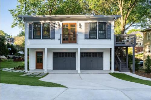 ein weißes Haus mit zwei Garagentüren und einer Veranda in der Unterkunft Butterfly Bungalow in Atlanta