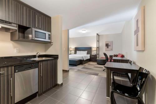 a kitchen and living room with a bed in a room at Best Western Plus Airport Inn & Suites in Saskatoon