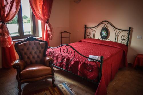 a bedroom with a red bed and a chair at Agriturismo Airone Eco Bio in Pitigliano