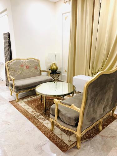 salon z 2 krzesłami i stołem w obiekcie Arsaad villa apparments w mieście ‘Ūd al Bayḑāʼ