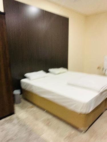 un letto con lenzuola e cuscini bianchi in una stanza di Arsaad villa apparments a ‘Ūd al Bayḑāʼ