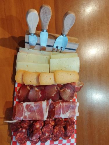 a tray of cheese and meat with spoons and forks at Complexo Alameda in Viveiro