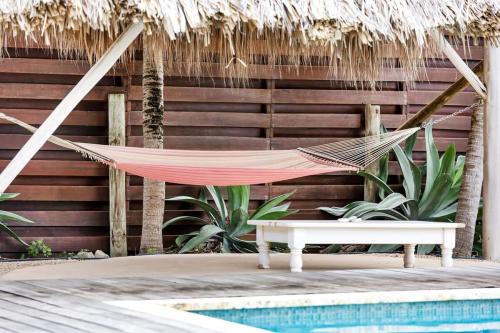 a hammock and a bench next to a pool at Villa Kromboon with an amazing sea view in Kralendijk