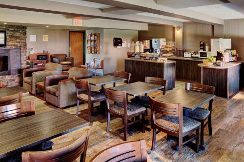 un restaurante con mesas y sillas de madera en Coast Fort St John Hotel, en Fort Saint John