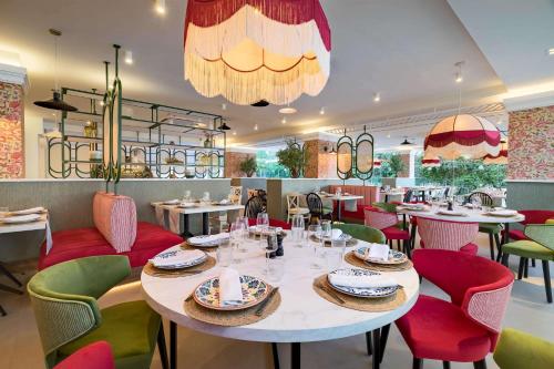 a restaurant with a large white table and colorful chairs at Occidental Puerto Banús in Marbella