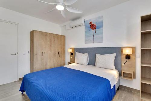 Turtles Place with Communal Pool في كراليندايك: غرفة نوم بسرير ازرق وبيض ومروحة سقف