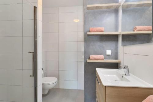 a white bathroom with a toilet and a sink at Kas Ereda Ground floor Apartment with Pool in Kralendijk