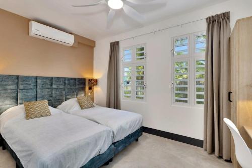 a bedroom with two beds and two windows at Kas Ereda Ground floor Apartment with Pool in Kralendijk