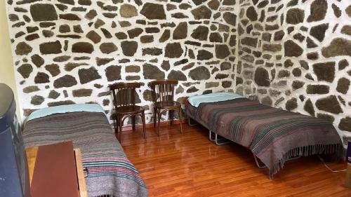 a room with two beds and a stone wall at Bitro House in Pogradec