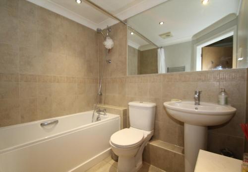 a bathroom with a toilet and a sink and a bath tub at Lovely ground floor apartment near Windsor & Ascot in Bracknell