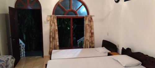 two beds in a room with a window at Ananda Villa Kosgoda Since 1995 in Kosgoda