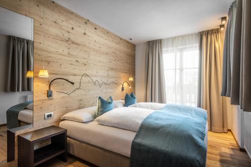 Chalet Prades Dolomiti Lodges في لا فيلا: غرفة نوم بسرير كبير وجدار خشبي
