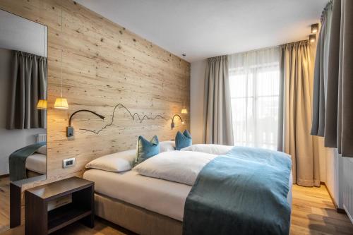 een slaapkamer met een groot bed en een houten muur bij Chalet Prades Dolomiti Lodges in La Villa