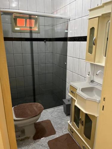 een badkamer met een douche, een toilet en een wastafel bij Casa Girassol in Praia Grande