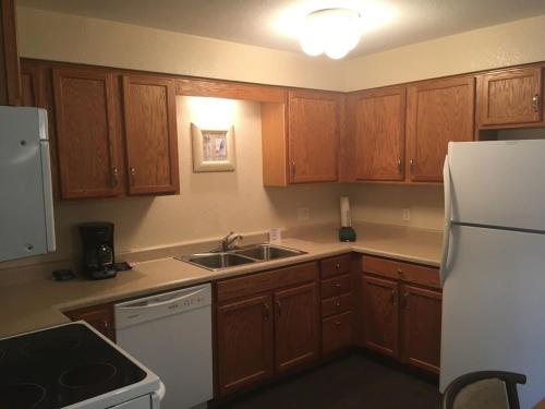 a kitchen with wooden cabinets and a white refrigerator at Lake View Condo with Pool and Hot Tub close to Grand Glaize Bridge at Lake Ozarks in Osage Beach