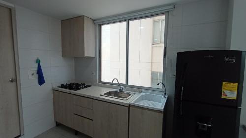 a kitchen with a sink and a black refrigerator at SUITES IN CARTAGENA QUiET LOCATION NEXT TO THE BEACH in Cartagena de Indias