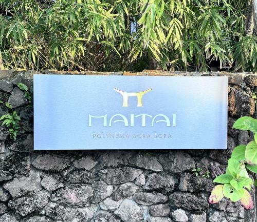 a sign for a hotel on a stone wall at Maitai Bora Bora in Bora Bora
