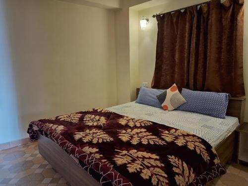 a bedroom with a bed with a brown blanket and blue pillows at Anand Niketan Homestay Shimla in Shimla