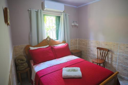 a bedroom with a red bed with two towels on it at Pousada Linda Flor in Alto Paraíso de Goiás