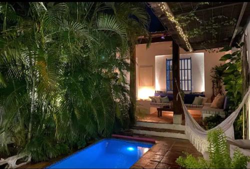 a house with a swimming pool and a hammock in a yard at Casa colonial en el exclusivo Alto del Rosario in Honda