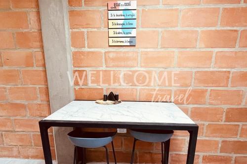 a table with two stools in front of a brick wall at Lotus Loft Itagui in Itagüí
