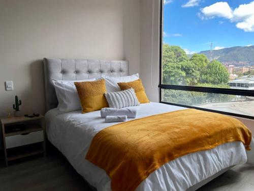 een slaapkamer met een bed en een groot raam bij Excepcional loft cerca del Parque La 93 in Bogota