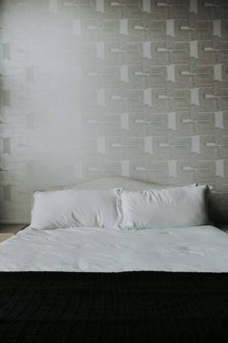 a bed with white pillows and a brick wall at Winner's Circle in The City in Lexington