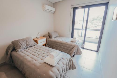two beds in a room with a window at 3) Hermoso departamento cómodo y equipado! in Godoy Cruz