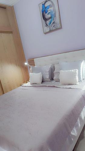 un letto bianco con lenzuola e cuscini bianchi di Appartement Basatine a Fes
