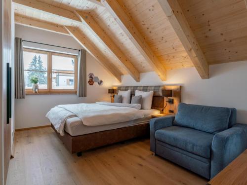 a bedroom with a bed and a blue chair at Alpenjoy Lodge in Donnersbachwald