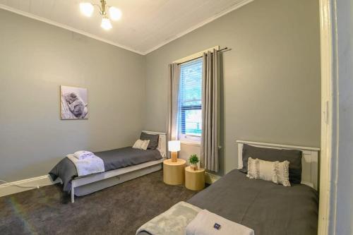 1 dormitorio con 2 camas y ventana en Darling St - Charming CBD Abode, Pet Friendly, en Dubbo