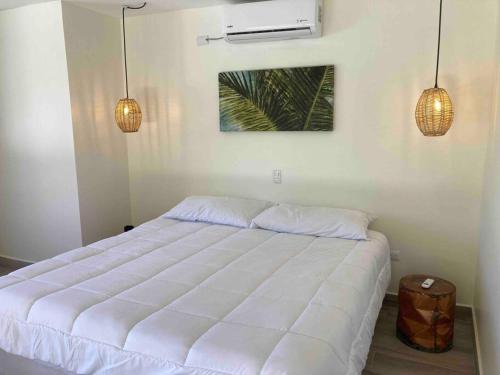 een wit bed in een slaapkamer met 2 hanglampen bij Marbella Forest Retreat apartment 1bed, 2ppl in Santa Cruz
