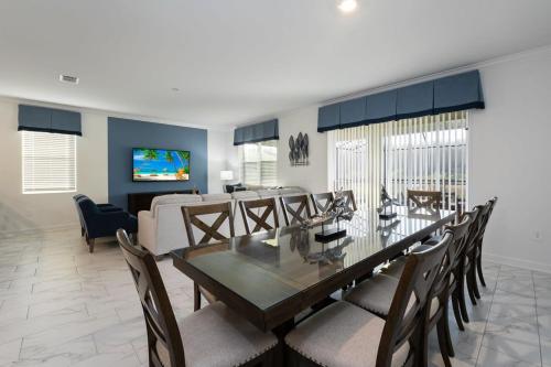 a dining room with a table and chairs and a living room at Amazing 8br w pool theater game room by Disney in Kissimmee
