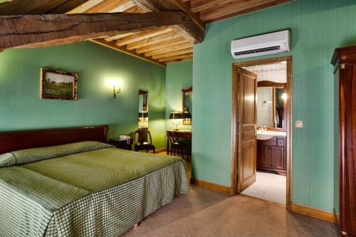 ボーヌにあるホテル ベル エポックの緑の壁のベッドルーム、ベッド、バスルームが備わります。