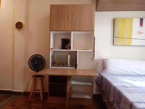 a room with a bed and a table with a microwave at Apartamento no Condomínio Imperial in Lambari