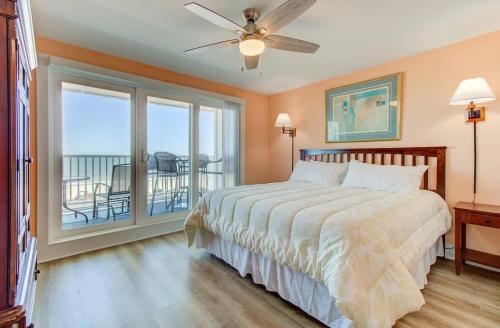 a bedroom with a bed and a balcony at Carolina Surf - 3BR Condo with Stunning Ocean Views in Carolina Beach