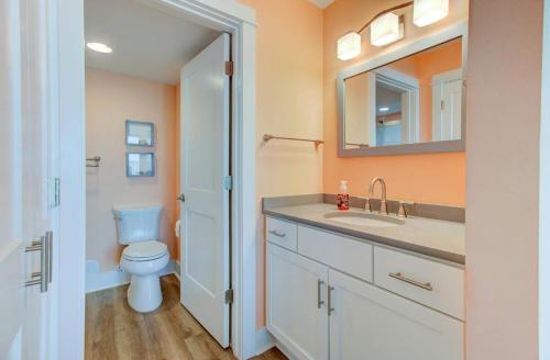 a bathroom with a toilet and a sink and a mirror at Carolina Surf - 3BR Condo with Stunning Ocean Views in Carolina Beach