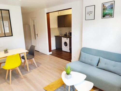 uma sala de estar com um sofá azul e uma mesa em Cozy 2-room 3 min from Mantes train station em Mantes-la-Jolie