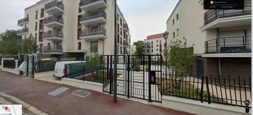 a fence in front of a building with a van at Elegancia Rueil, 20 min de Paris La Défense, quartier recherché, Lac in Rueil-Malmaison