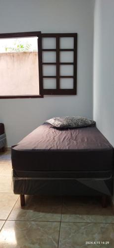 a bed sitting in a room with a window at Casa das orquídeas in Santana do Riacho