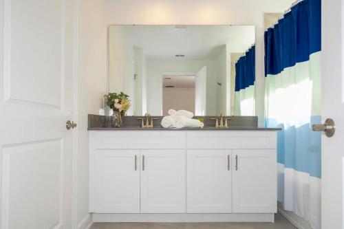 ein Bad mit einem Waschbecken und einem Spiegel in der Unterkunft WonderFul 4Bd Near Disney w Pool at StoreyLake 2557 in Kissimmee