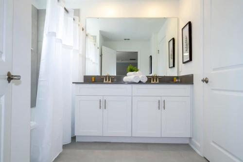 uma casa de banho branca com um lavatório e um espelho em Fantastic 4 Bd w Pool at Storey Lake Resort 2709 em Kissimmee