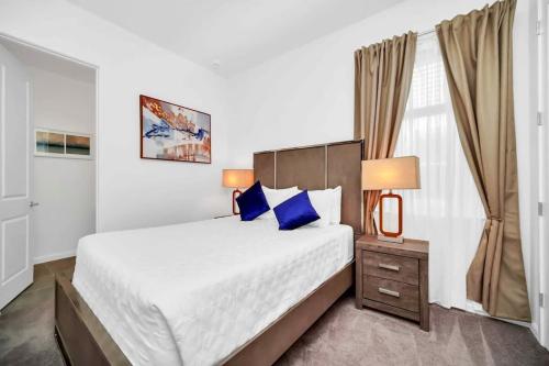 - une chambre avec un grand lit et des oreillers bleus dans l'établissement Stunning 12Bd Sleeps 25 w Pool Close to Disney at Veranda Palms 4405, à Kissimmee