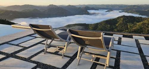 deux chaises assises au sommet d'une montagne avec des nuages dans l'établissement Hacienda JM's, 