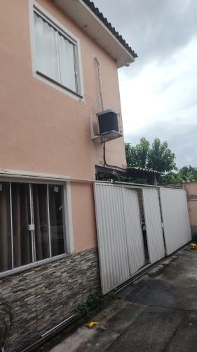 a pink house with a white fence and a gate at Casa 2 quartos na Taquara -Duque de Caxias in Duque de Caxias