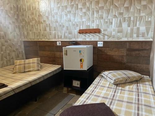 a room with two beds and a small refrigerator at Pousada Familia Aparecida in Aparecida