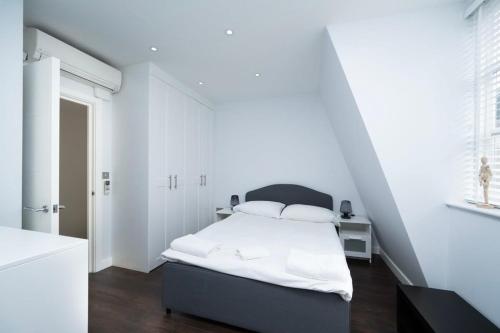 a white bedroom with a bed with white sheets at Stylish 3BR Flat in the Heart of Soho London in London