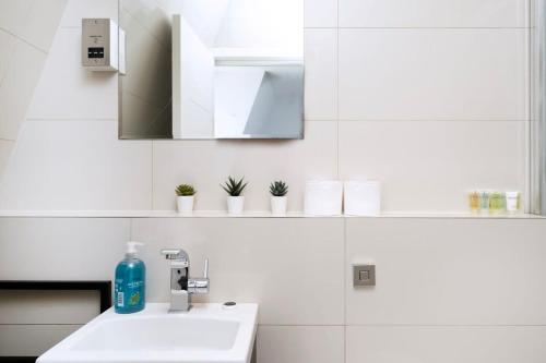 La salle de bains blanche est pourvue d'un lavabo et d'un miroir. dans l'établissement Stylish 3BR Flat in the Heart of Soho London, à Londres